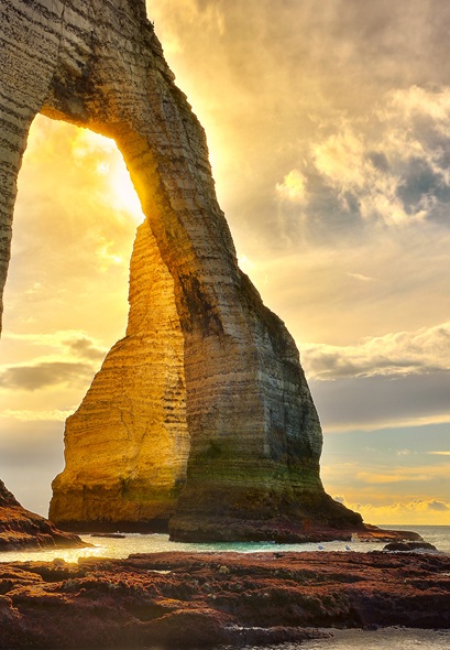 Arche rocheuse naturelle au bord de la mer illuminée par un coucher de soleil spectaculaire