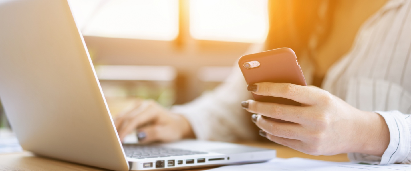 Personne utilisant un smartphone et un ordinateur portable dans un environnement de travail